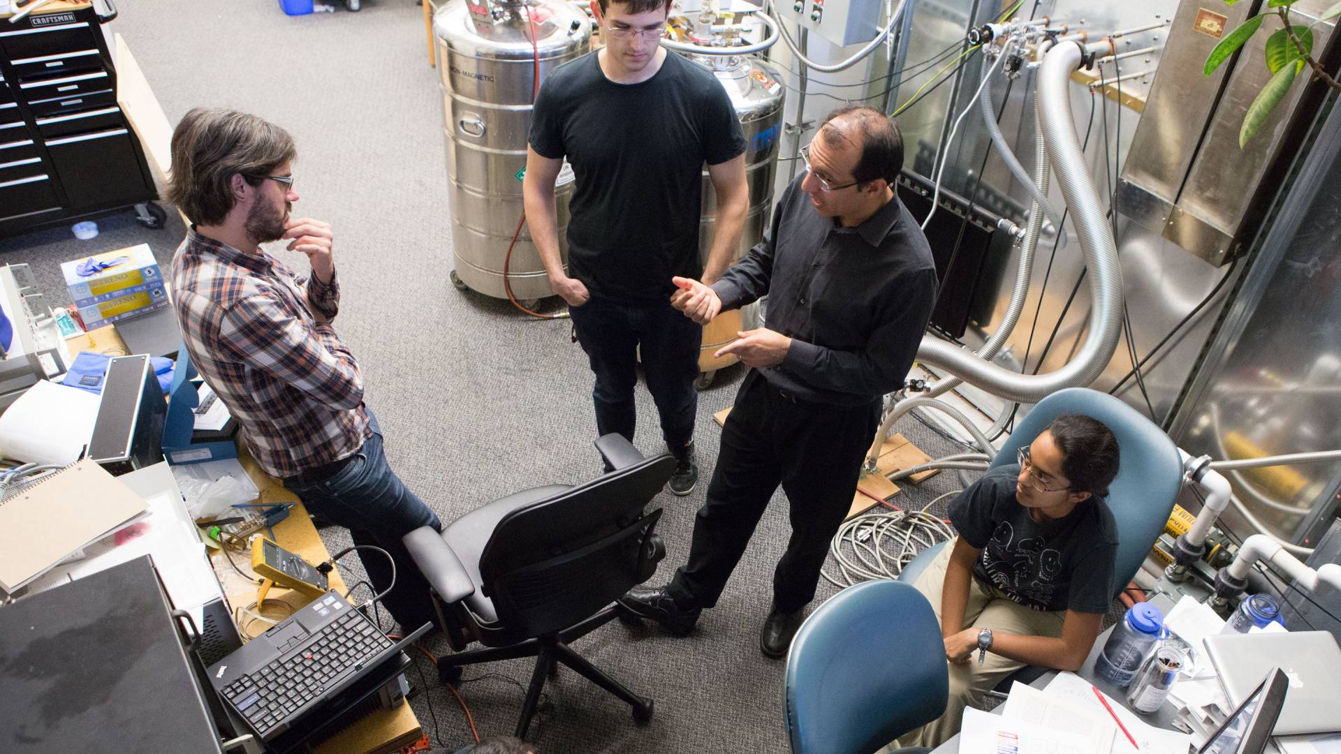 Professor and students confer in a lab.