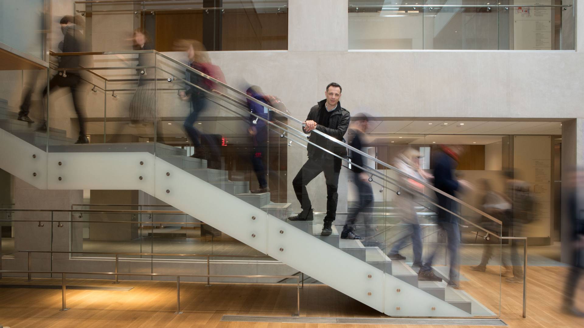 Dalton Conley on stairs with people moving past him