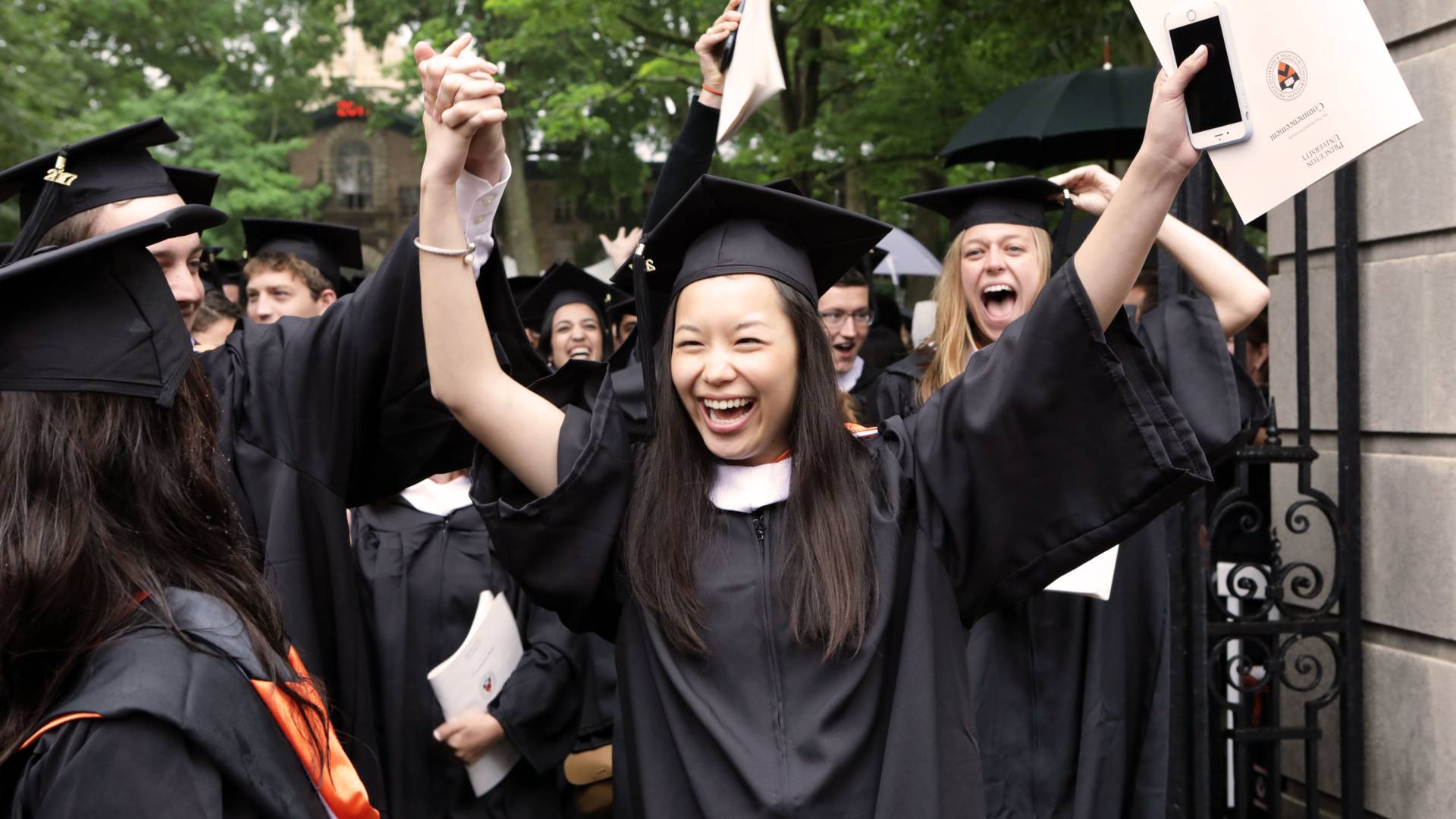 Student walks through gate with arms up cheering