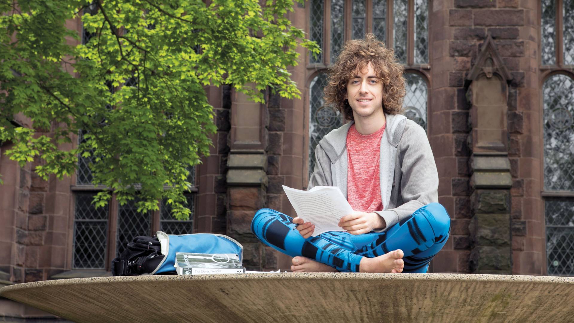 Kyle Berlin sitting outside on sculpture