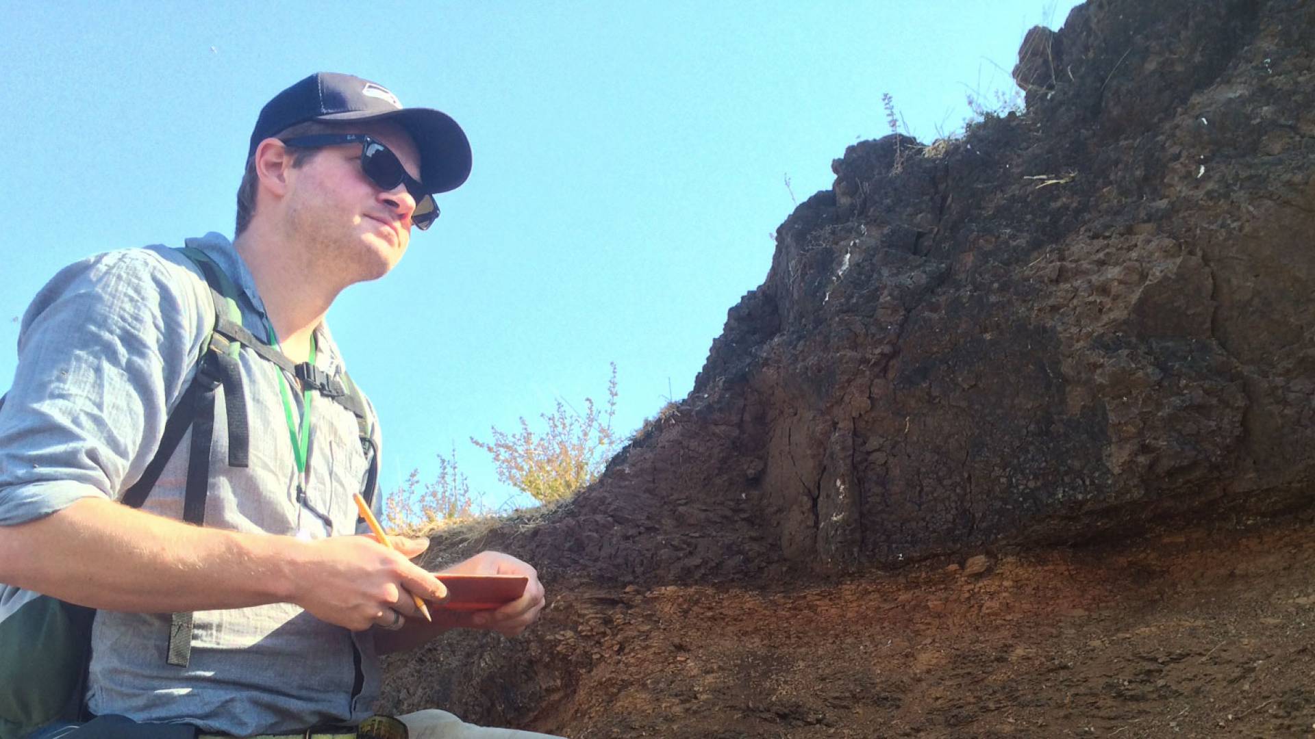 Blair Schoene standing by lava rock wall