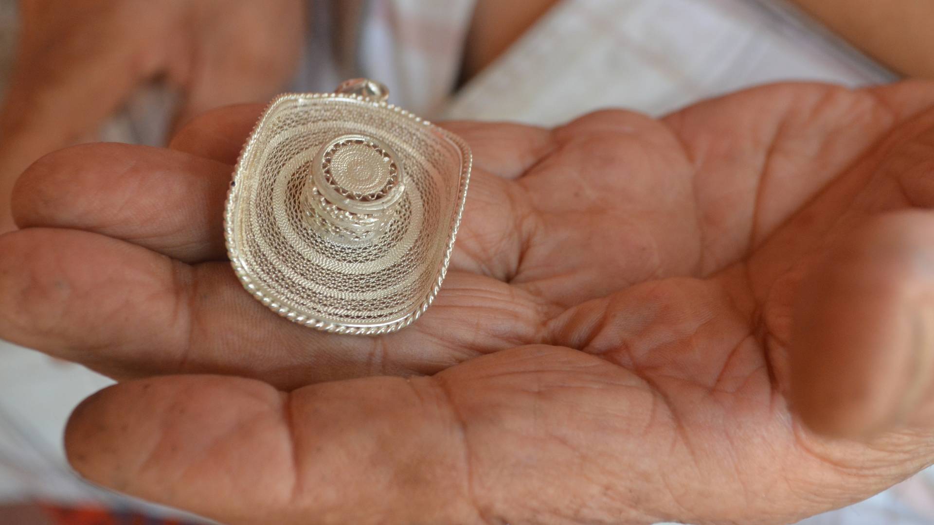 Miniature straw hat in palm of elderly man's hand