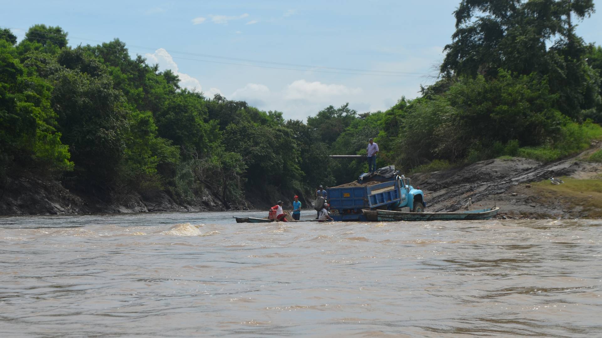 Men with dump truck standing in river