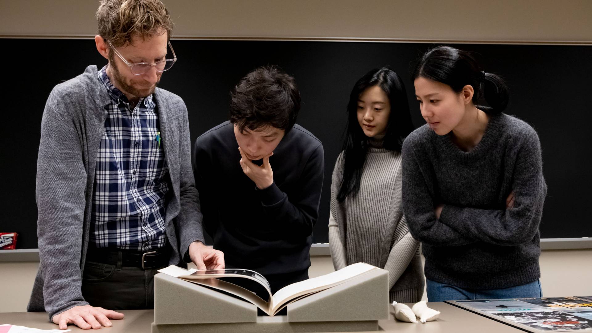 Franz Prichard standing with three students, looking at Japanese magazines