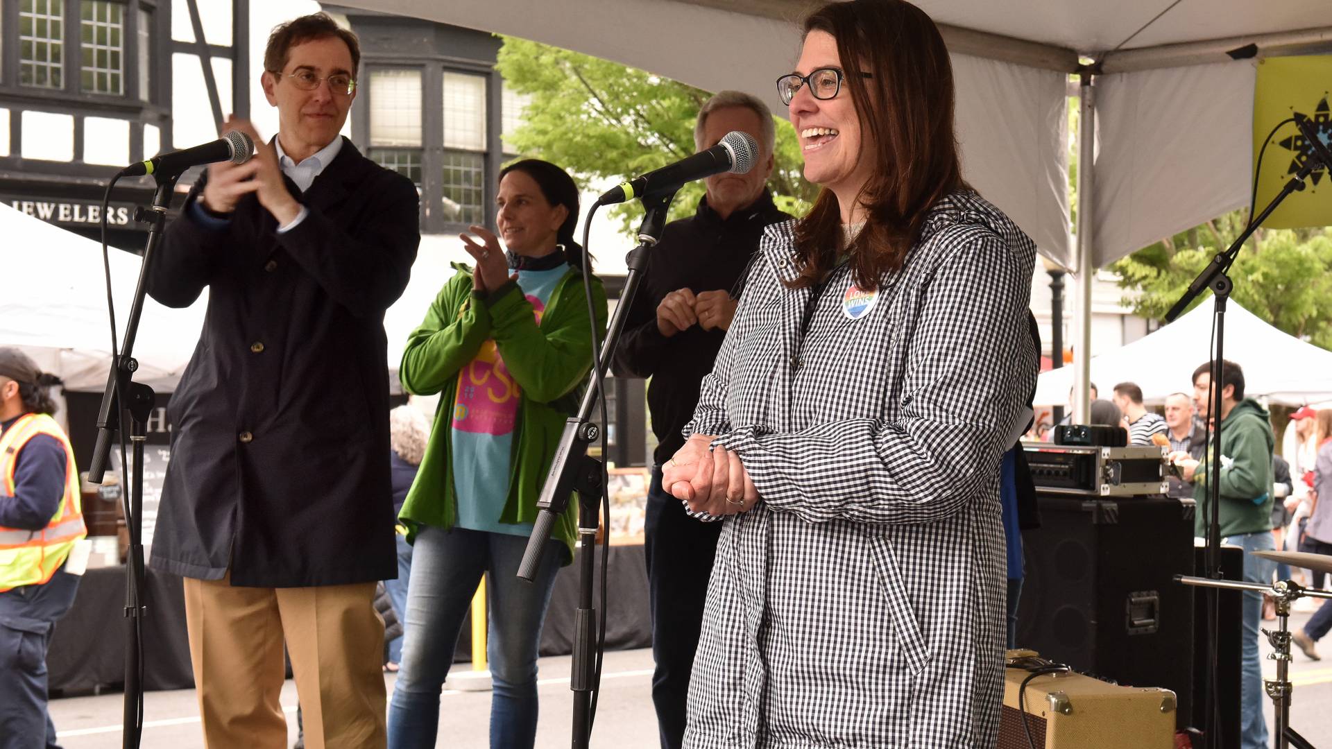 Mayor Lempert speaks into a mircophone under a tent at Communiversity