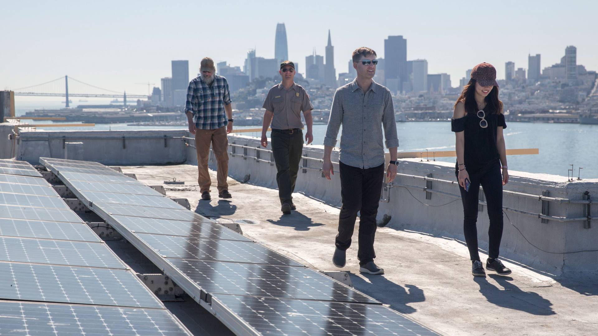 Darren Hammell and Isla Han walking on rooftop at Alcatraz with city skyline in the background