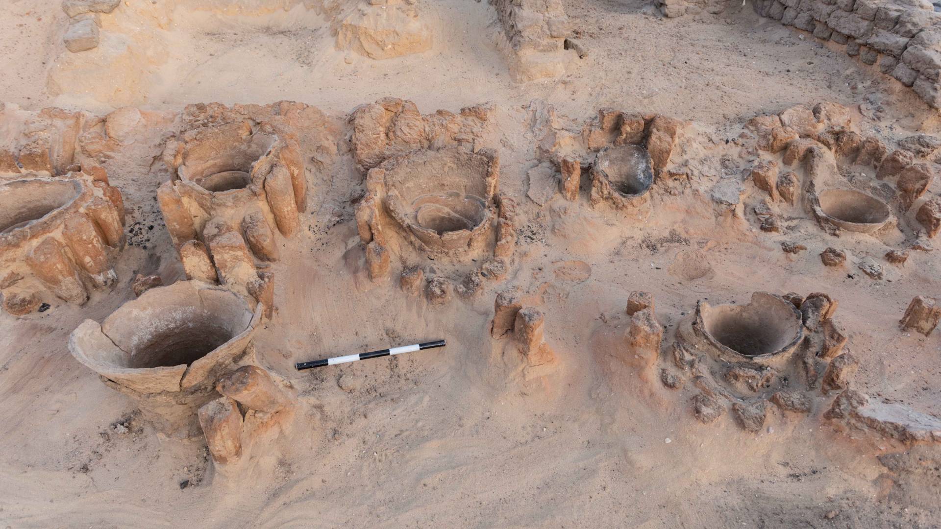 Openings of urns used to hold ingredients for brewing visible in the sand
