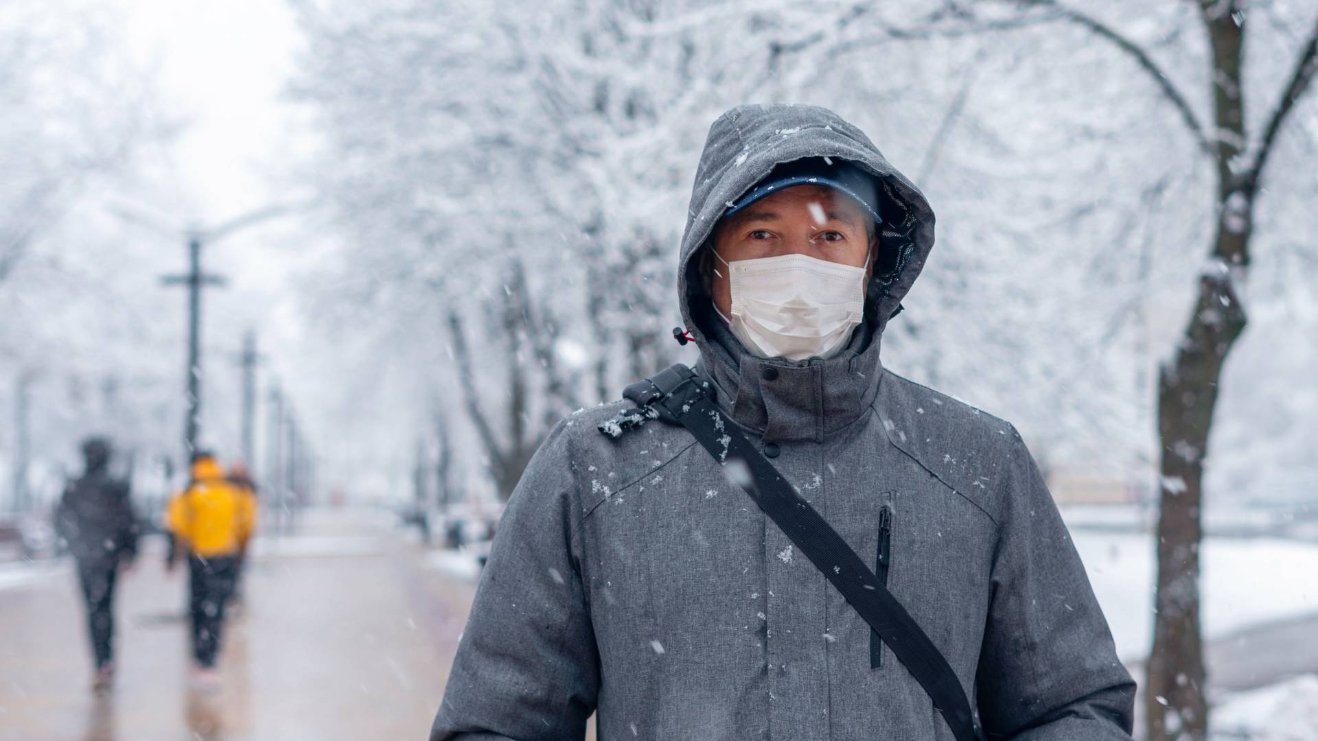 A masked person stands on a snowy walking path