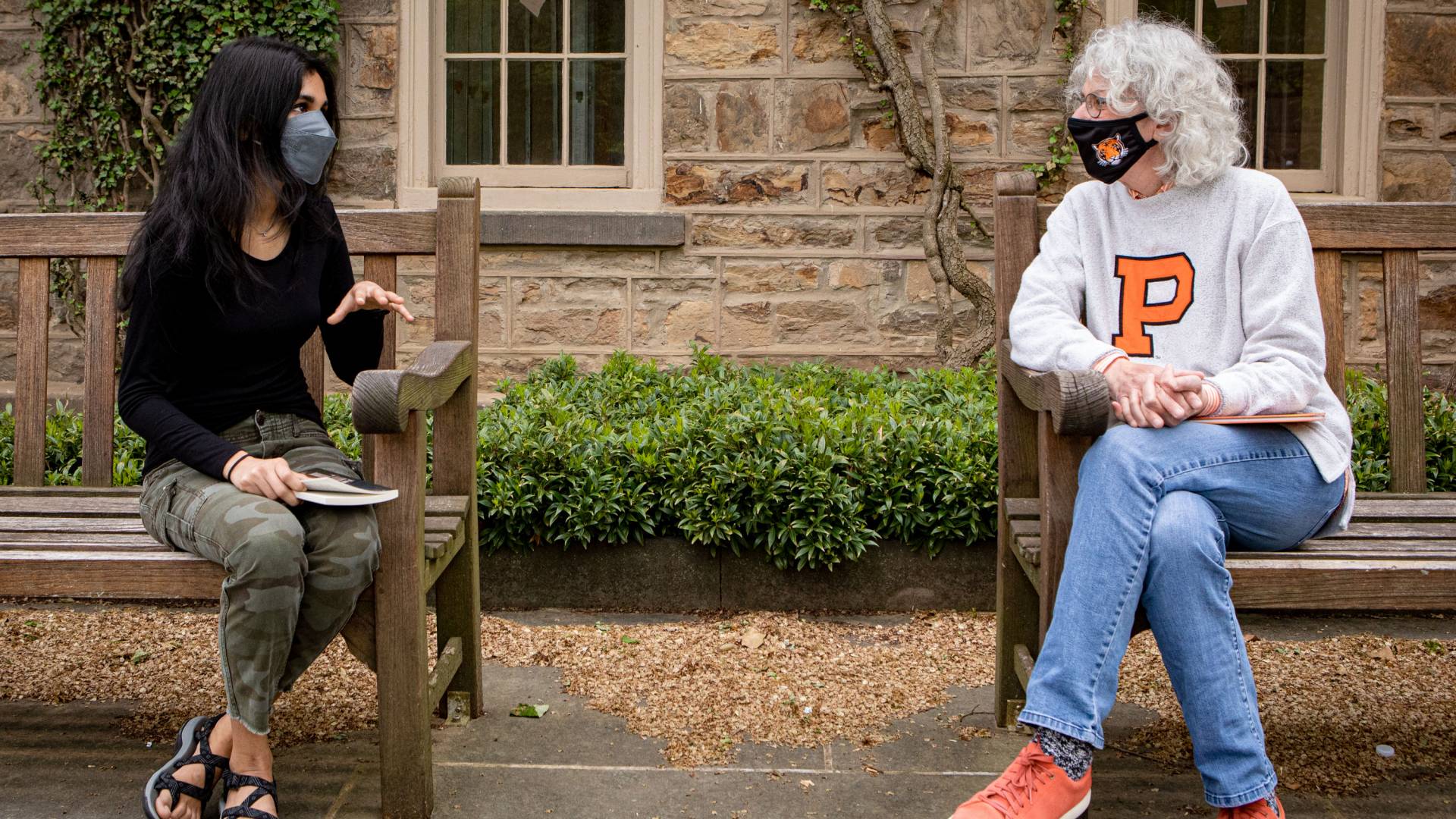 Student and Jill Dolan chat while sitting on benches