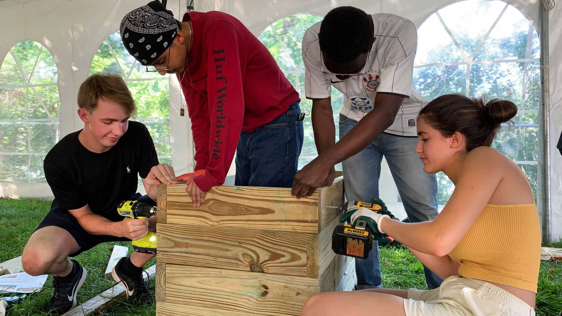 four students work on a wooden structure