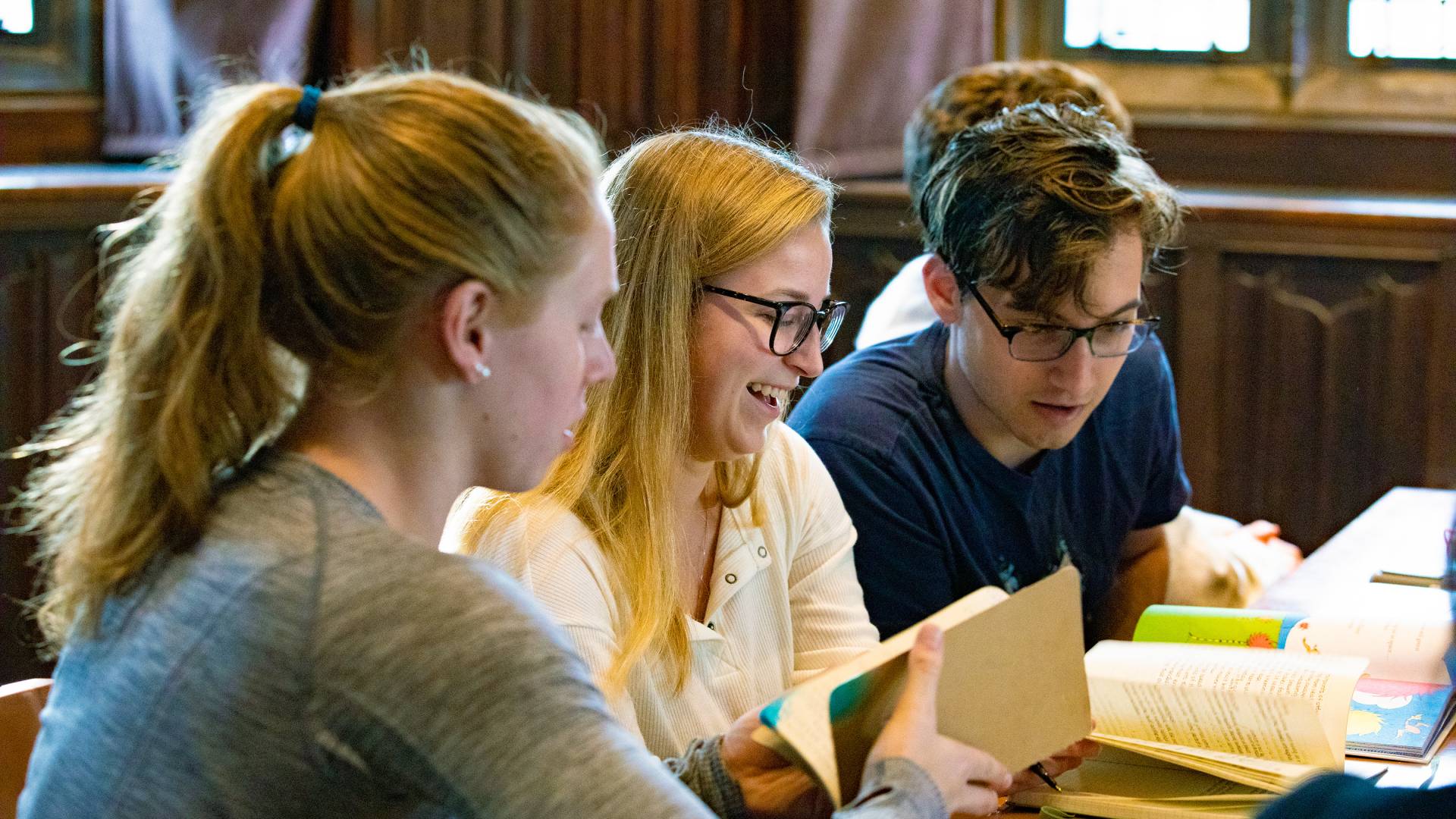 Students meeting to study literature from books they hold.