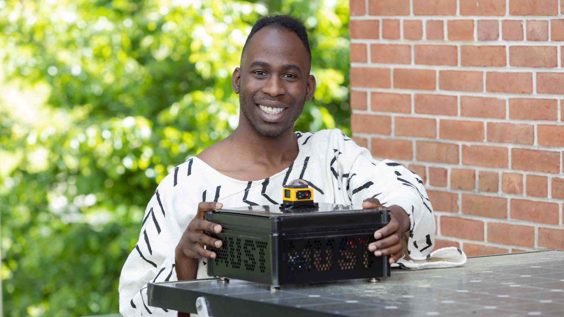Jovan smiling with the device he used for his thesis
