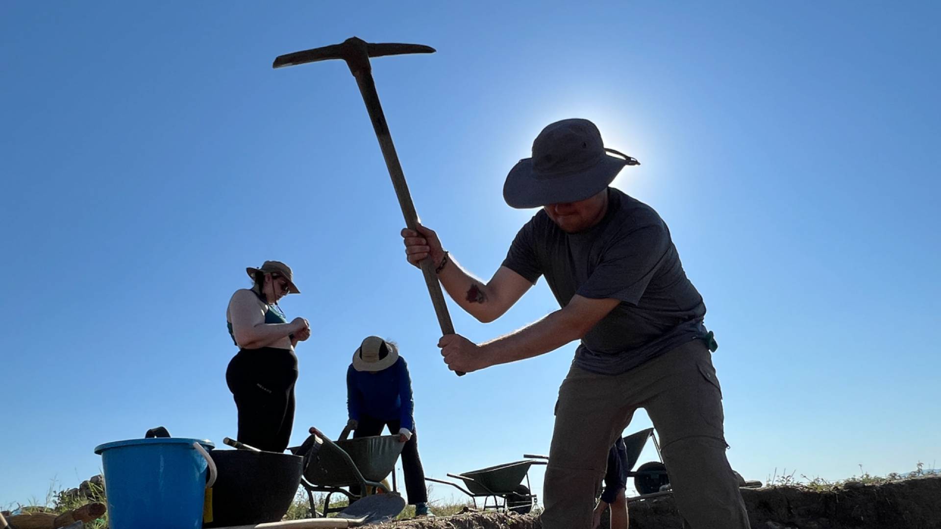 Group of people digging, pickaxe at hand.