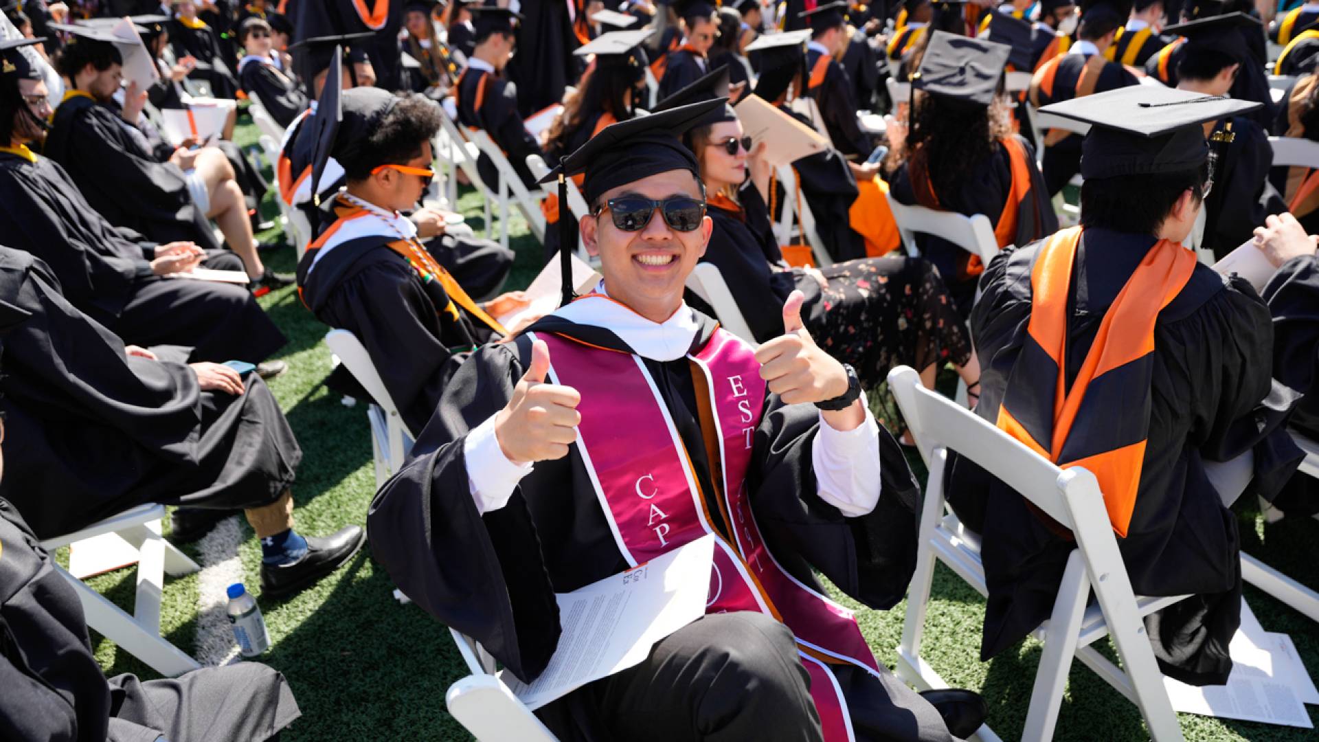 Male students doing two thumbs up