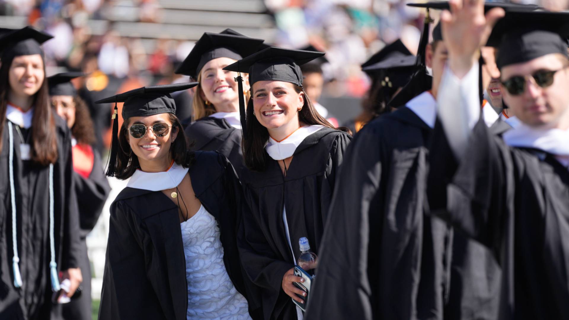 Students in cap and gown smiling at 2024 Commencement 