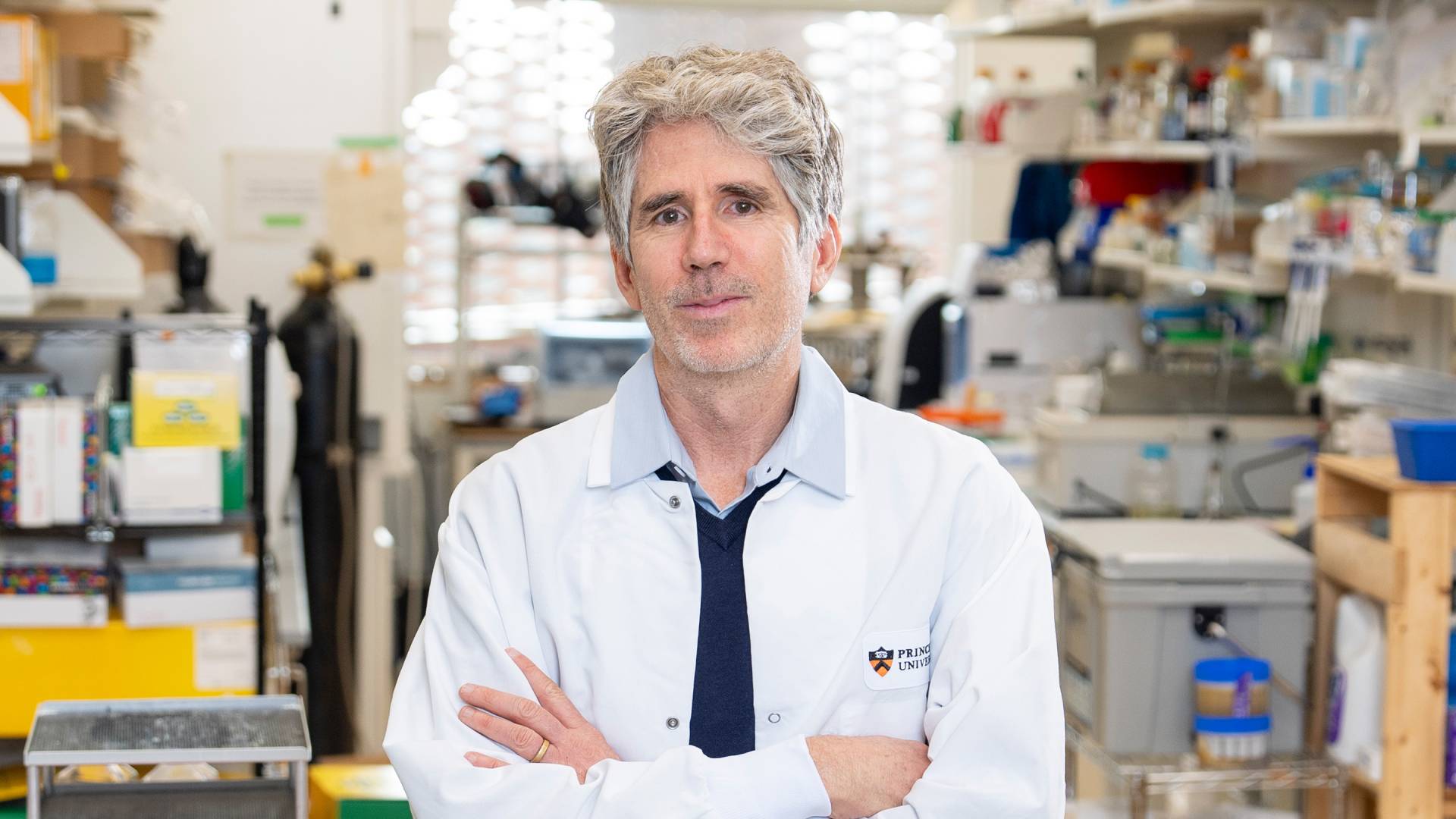 Joshua Rabinowitz stands in his lab, surrounded by glass vials and other research equipment.