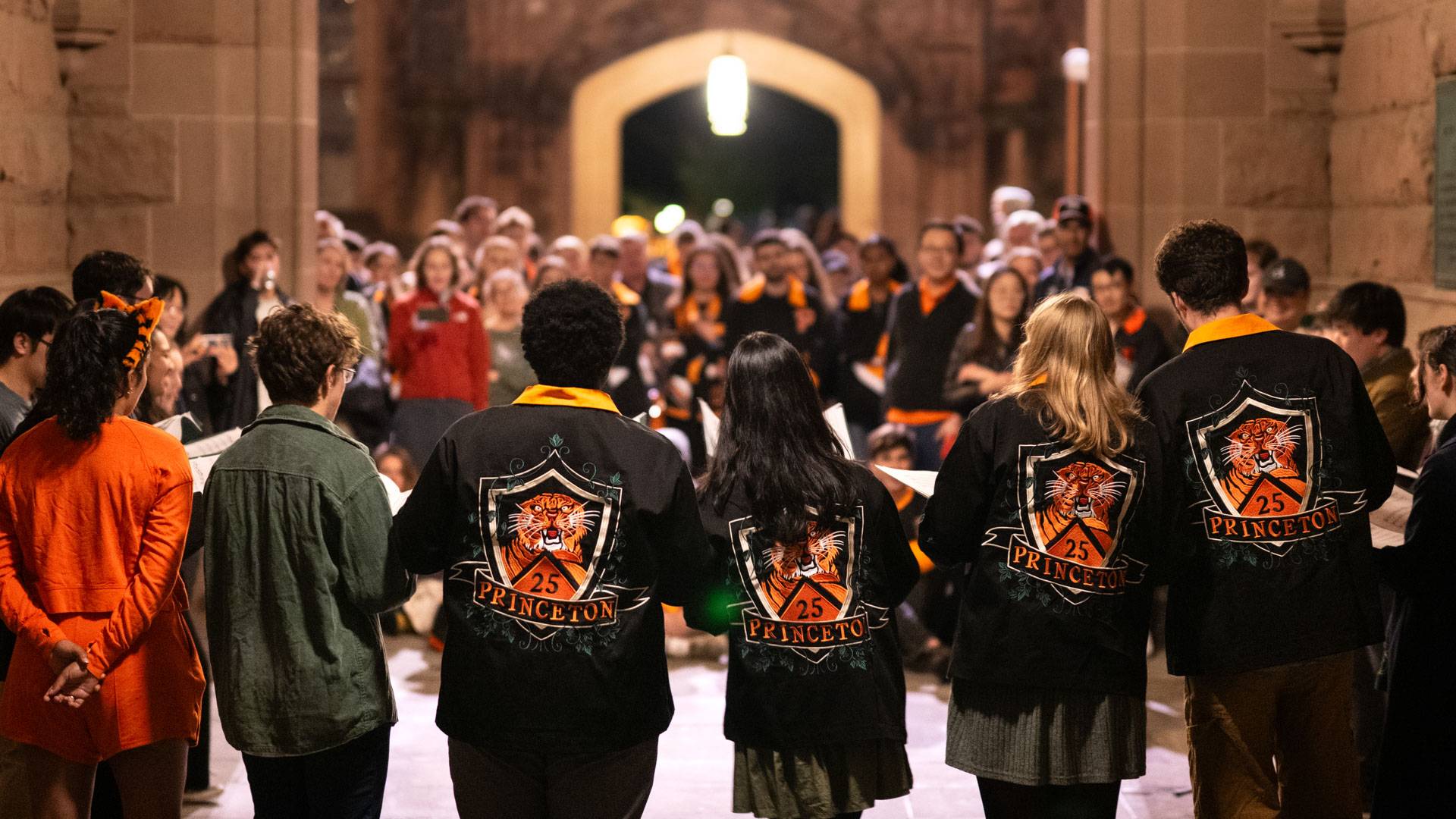 Students sing under an archway 