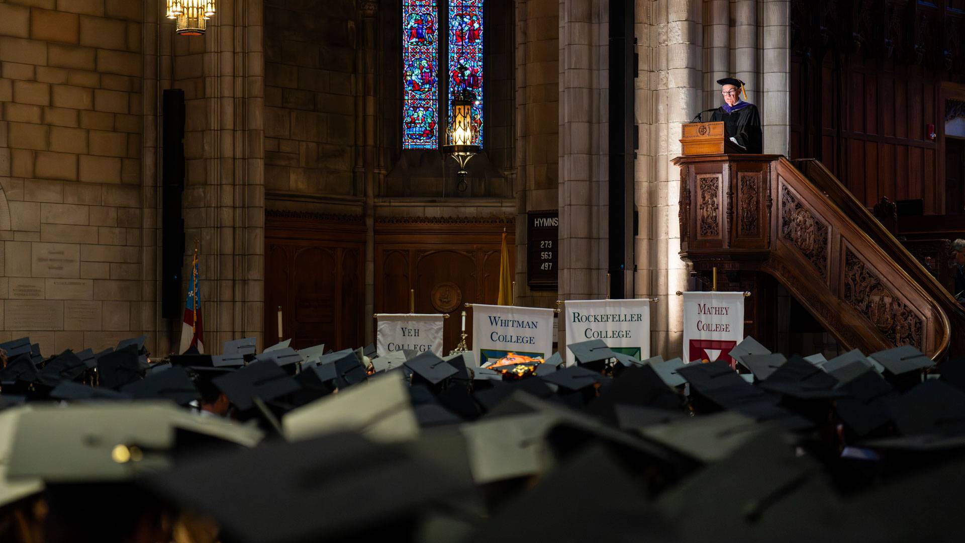Powell speaks to the graduates from an elevated podium.