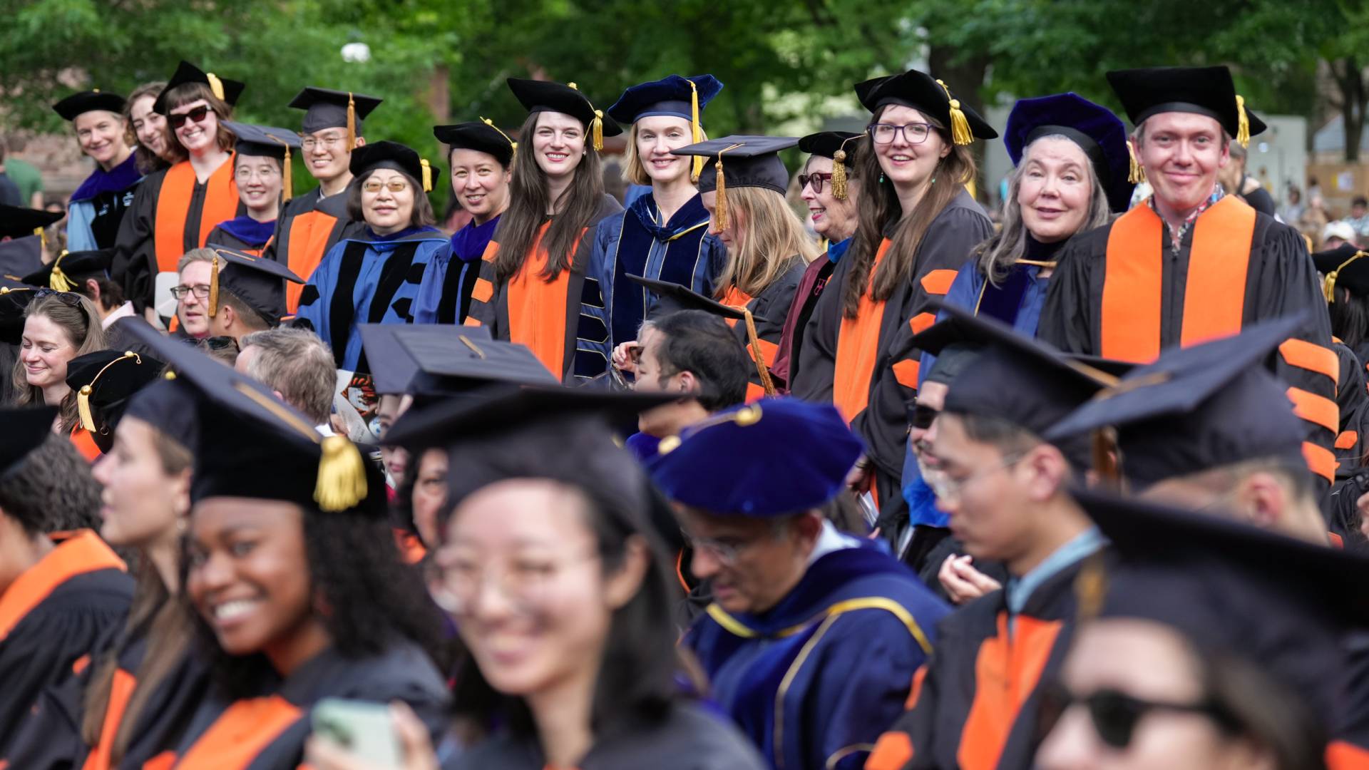 A line of people in colorful Ph.D. regalia.