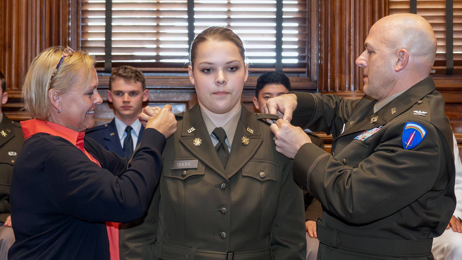 An Army ROTC student is pinned on both sides of her uniform by her civilian mother and Army Colonel father.
