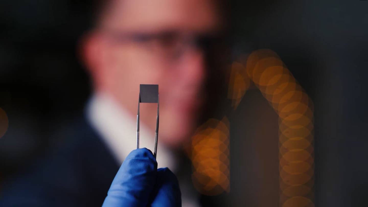 Fingertip size computer chip being held with tweezers by a gloved hand