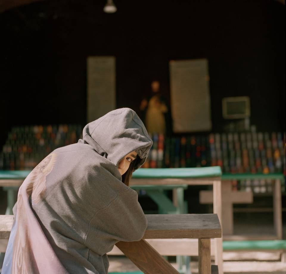 Student in hooded sweatshirt looking back at camera