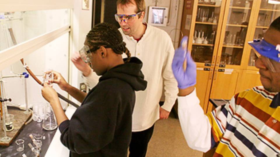 Bernhard helps student working under a fume hood