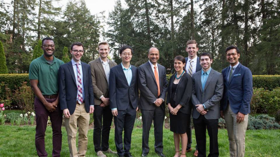 Graduate school teaching honorees pose with Dean of the Graduate School Sanjeev Kulkarni, standing on a lawn.