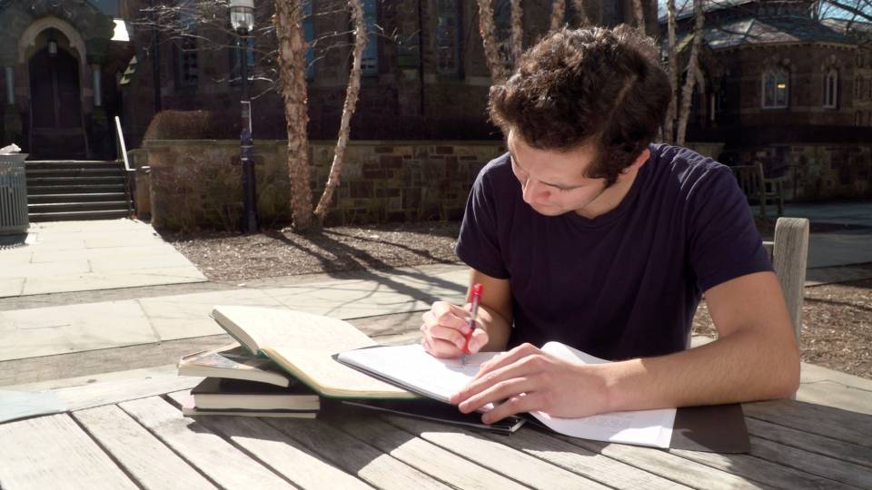 Edwin Rosales writing at table outside