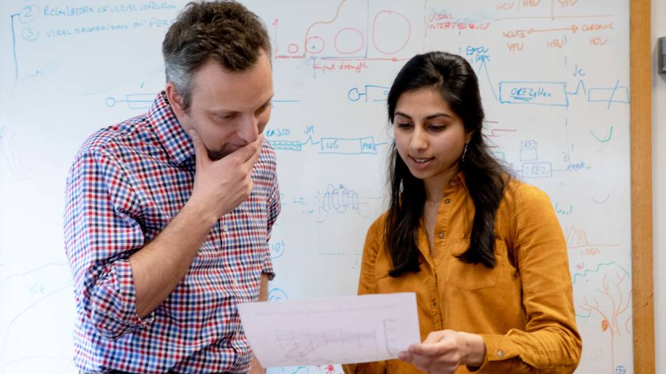 Alexander Ploss and Ila Nimgaonkar looking at paper