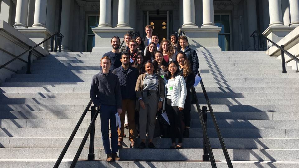 A group of students pose for a photo on the steps of the Eisenhower Executive Office Building in Washington DC