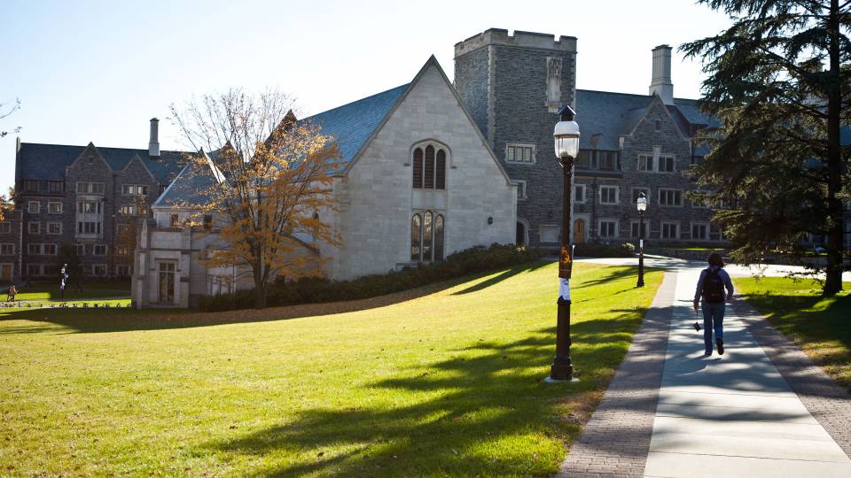 a student walks on campus on a sunny day
