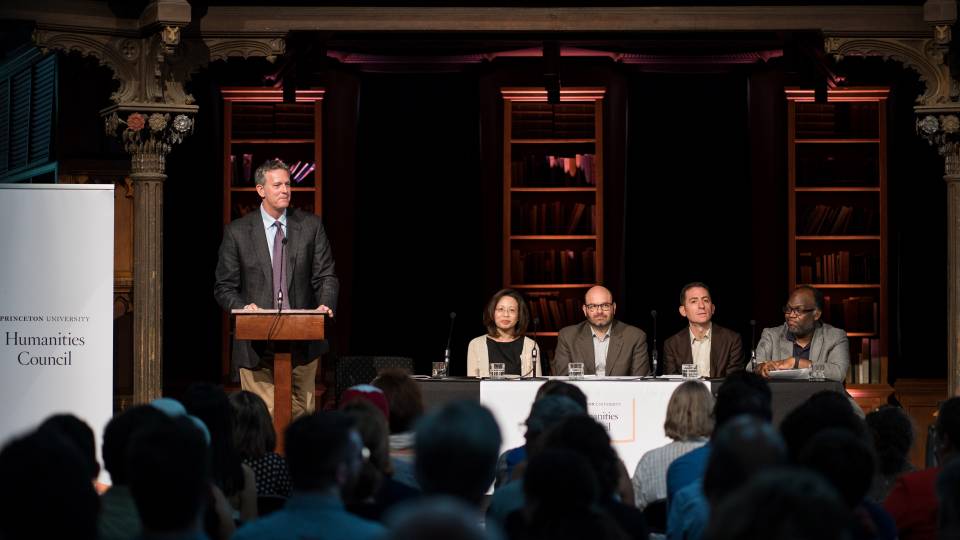 Prof Eric Gregory speaks at the podium with a faculty panel beside him