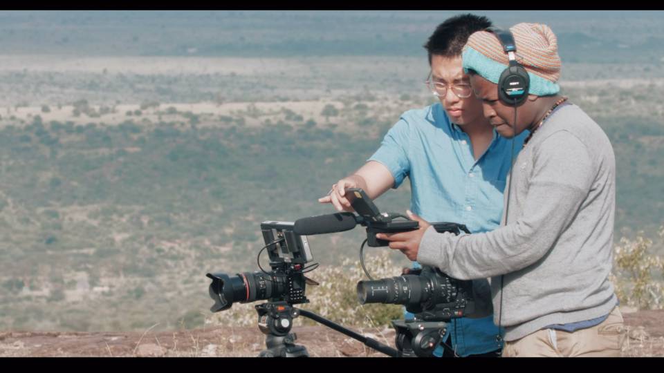 2 students look through a video camera in Mpala