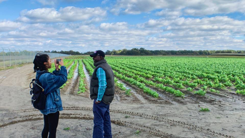 A student interviews a farmer in his field