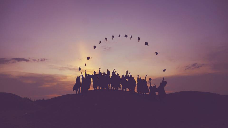 Students in their gowns, throwing up their mortarboards