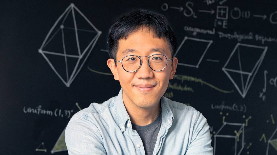 June Huh in front of a chalkboard