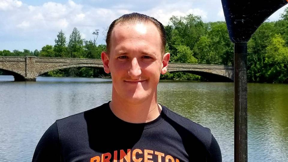 Student holding black and orange rowing oar