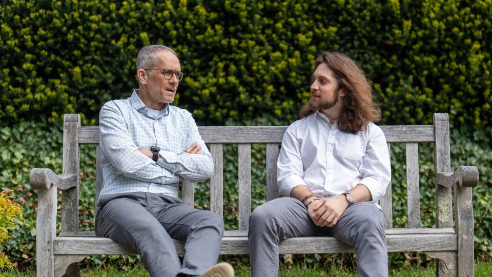 Ethan with his adviser sitting on a bench, talking.