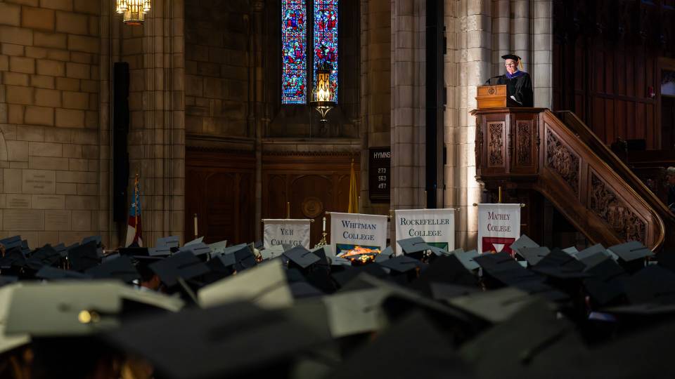 Powell speaks to the graduates from an elevated podium.