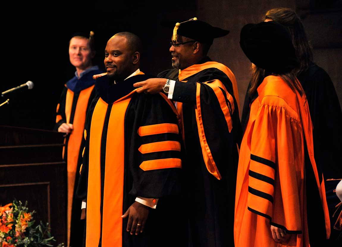 Clifton Granby is given his hood by Professor Glaude