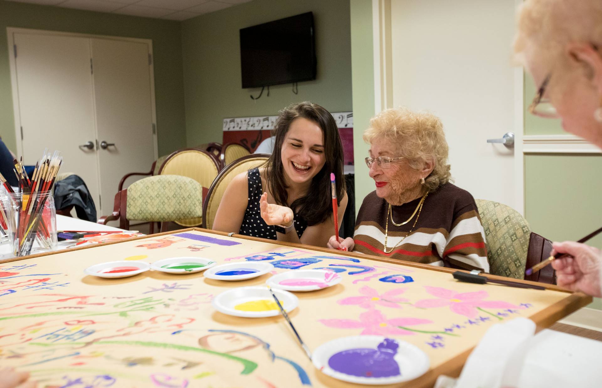 Student helping Brandywine Living resident paint