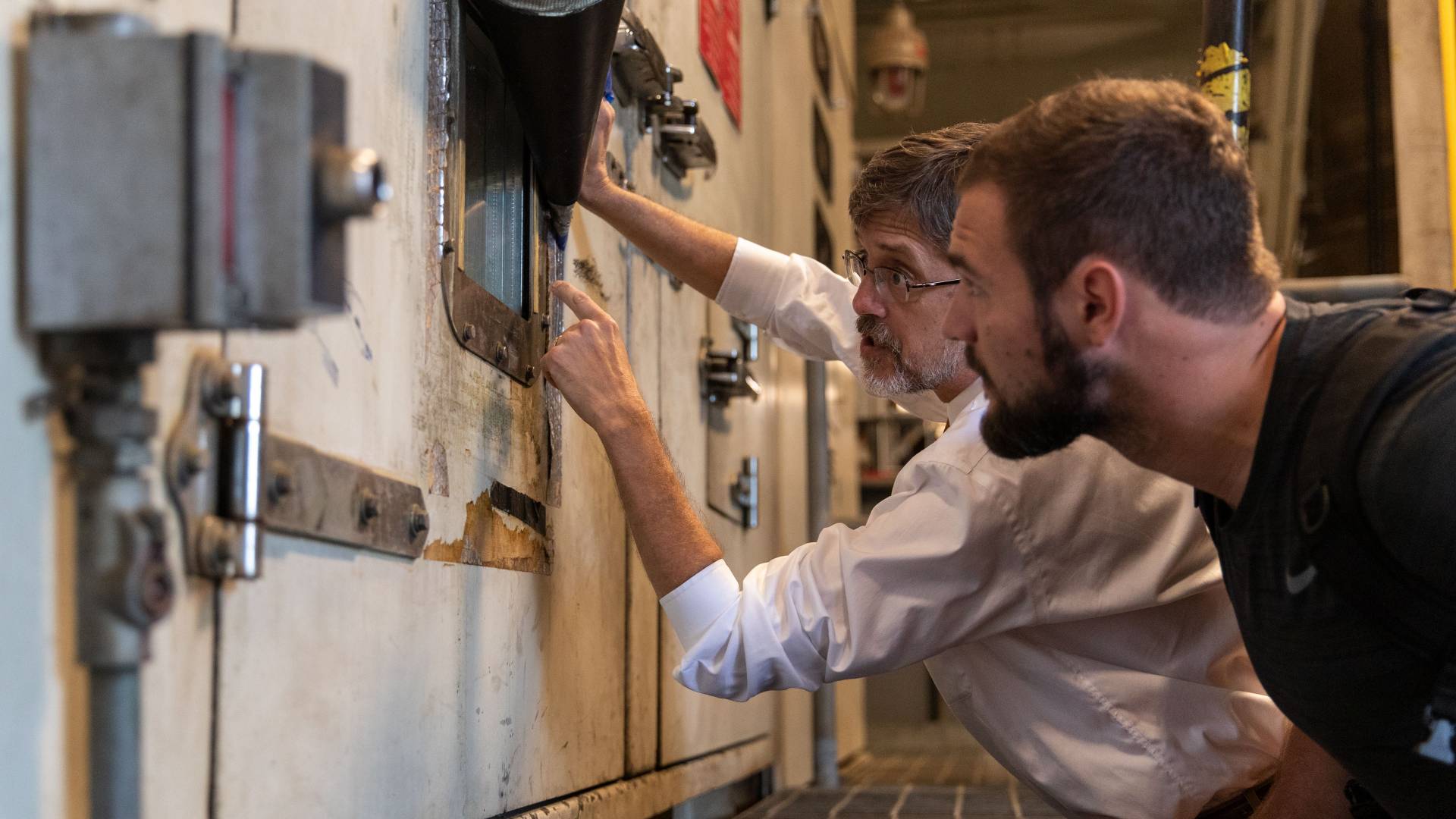 Ted Borer and student looking through porthole at Cogen plant