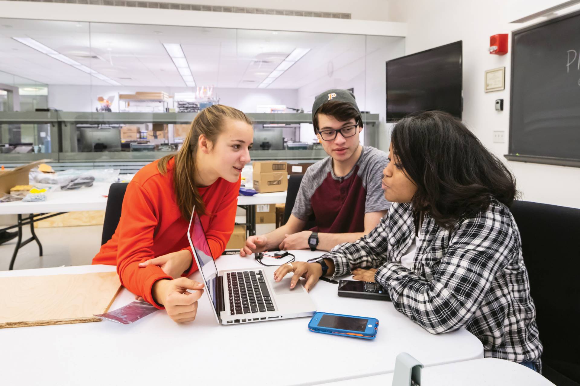 3 students discuss over a laptop