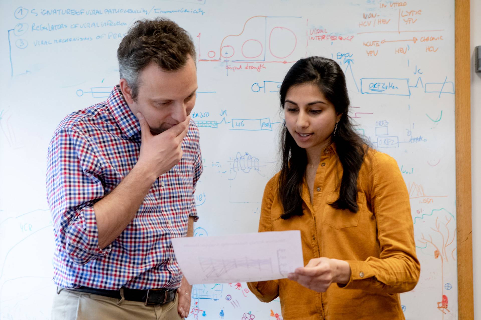 Alexander Ploss and Ila Nimgaonkar looking at paper