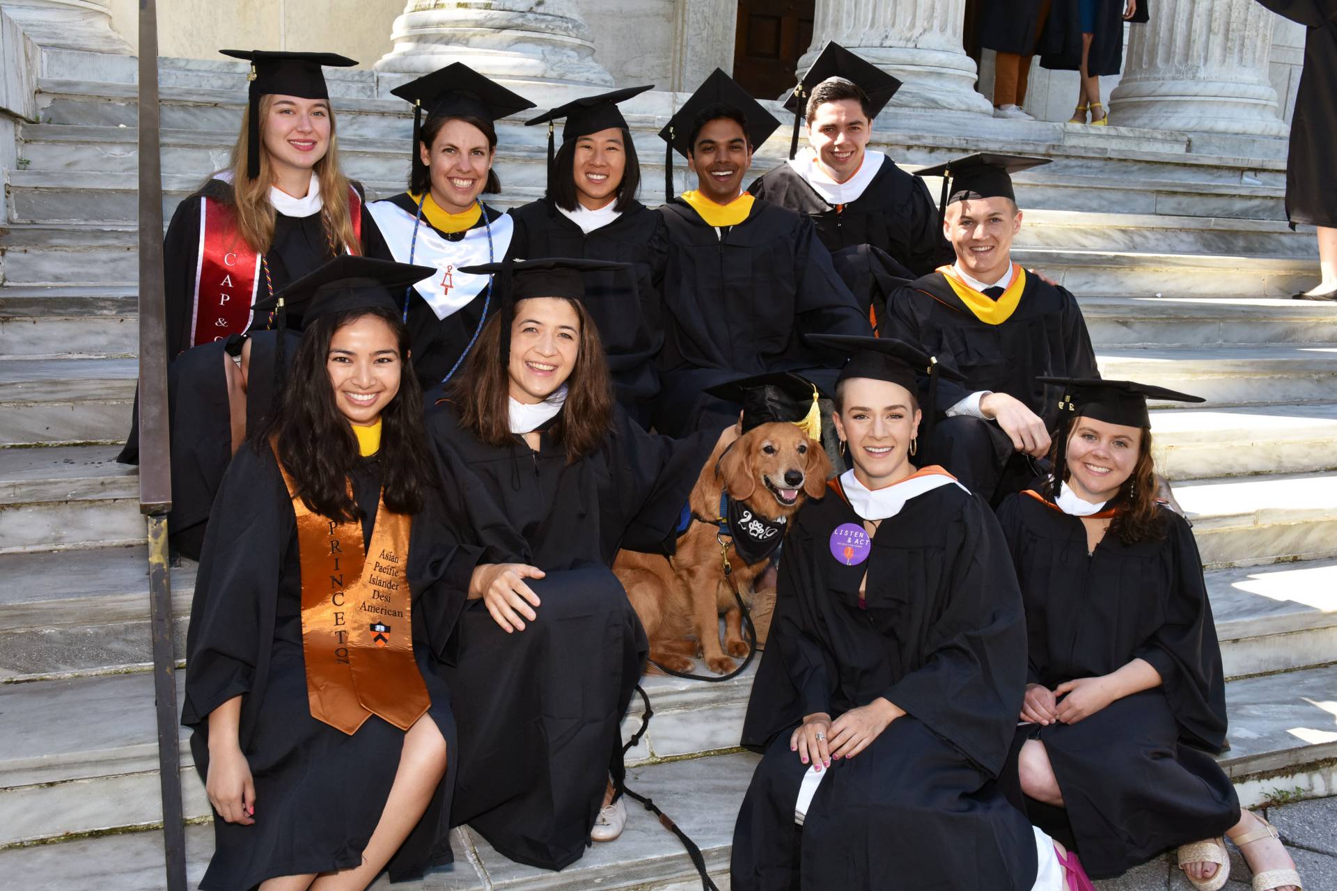 Camden Olson sitting on the steps of Clio Hall with friends and Koa