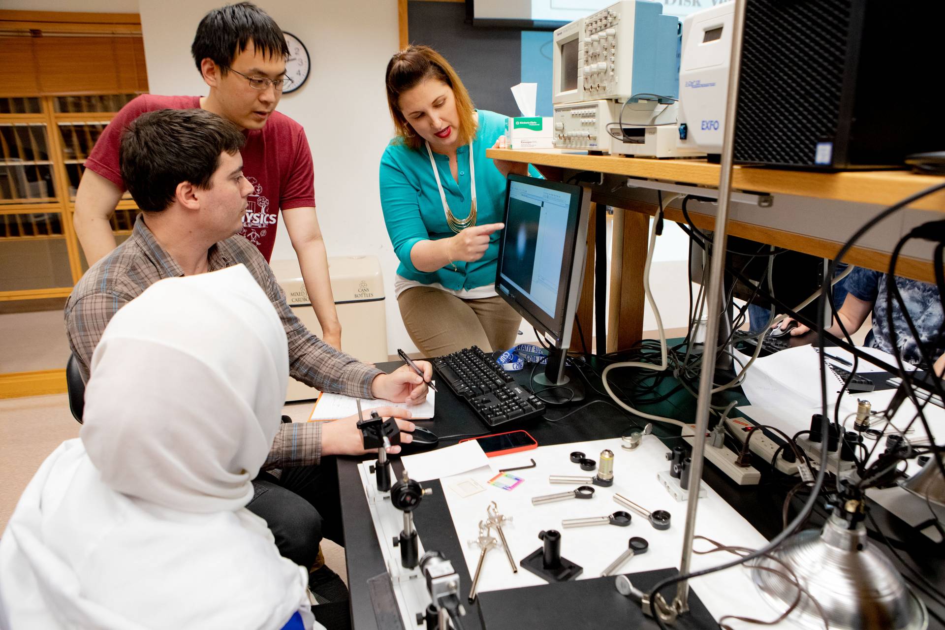 A lecturer explains a concept to 3 students in a lab
