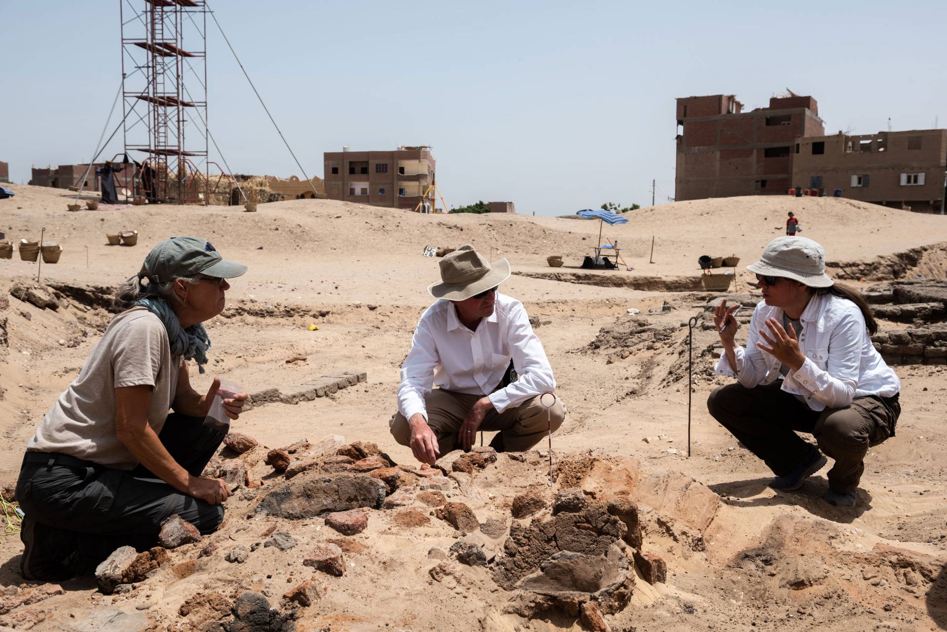 3 people in coversation while on archeological dig