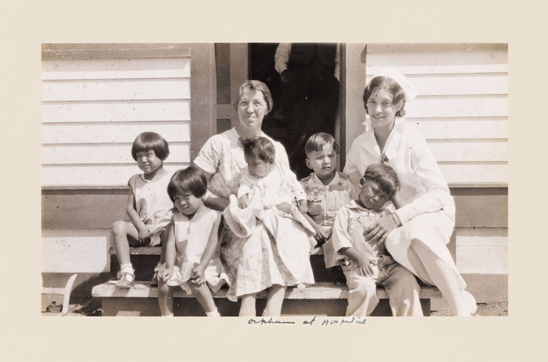 Two nurses sit on steps with small children