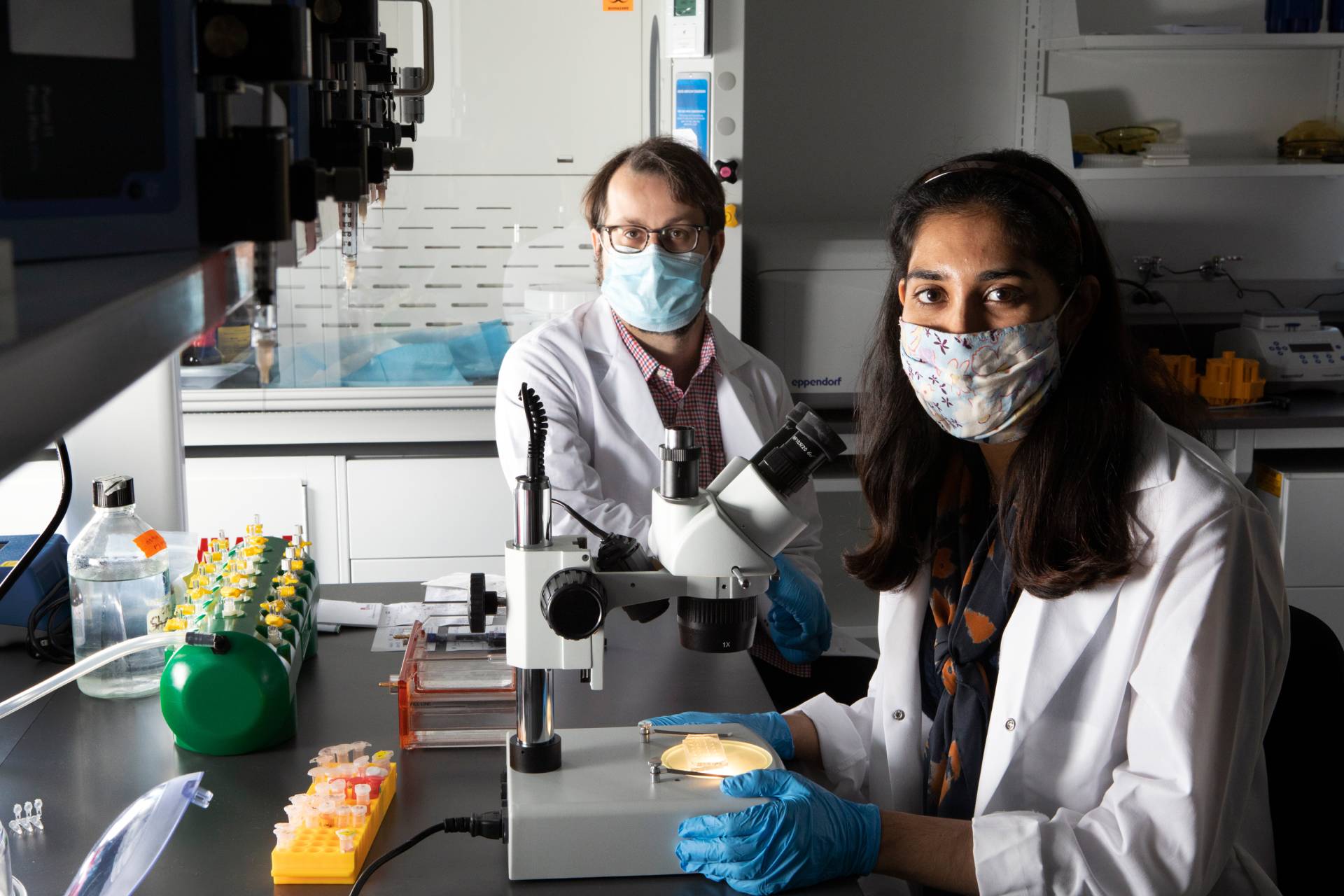 Man and a woman both masked in a lab